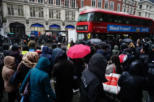 People wait to get on a bus outside a Tube station in central London during the strike