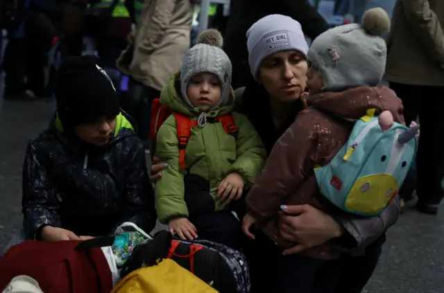 A mother waits with her children at the main hall of the Central train station in Warsaw