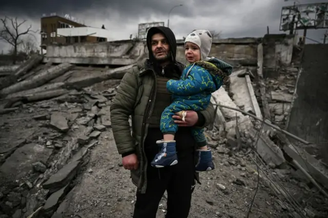 A man holds a child as he flees the city of Irpin, west of Kyiv