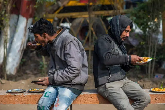 Two daily wage laborers seen eating food at a subsidized food center in Vashundhara