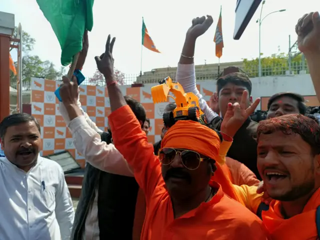 A BJP party worker seen with a toy bulldozer on his head.