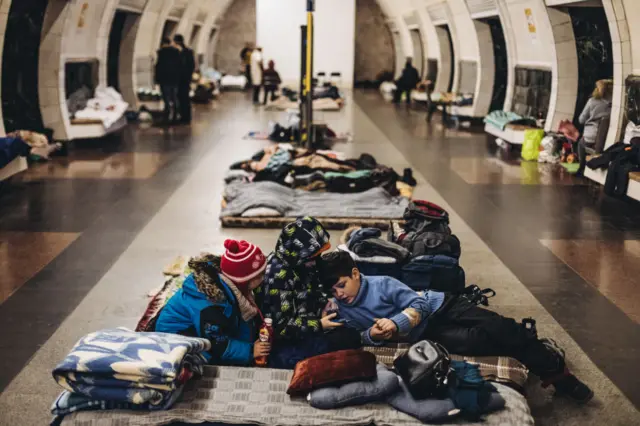 Children gather together on blankets and sleeping bags while sheltering in an underground metro station in Kyiv