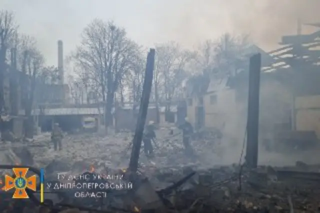 Rescue workers pictured engulfed in plumes of smoke as they stood amidst the blackened structures of buildings