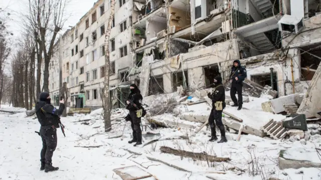 Ukrainian policeman take pictures outside a bombed building in Kharkiv