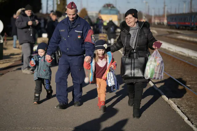 : A Hungarian police officer helps families as they arrive at Zahony train station after fleeing Ukraine on March 12, 2022 in Zahony, Hungary.