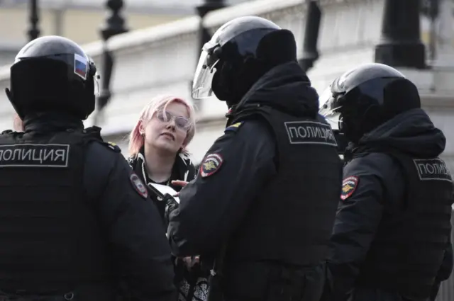 Police officers check a woman during a protest against Russian military action in Ukraine, in Manezhnaya Square in central Moscow on March 13, 2022.