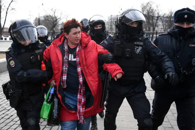 Police officers detain a woman during a protest against Russian military action in Ukraine, in Manezhnaya Square in central Moscow on March 13, 2022