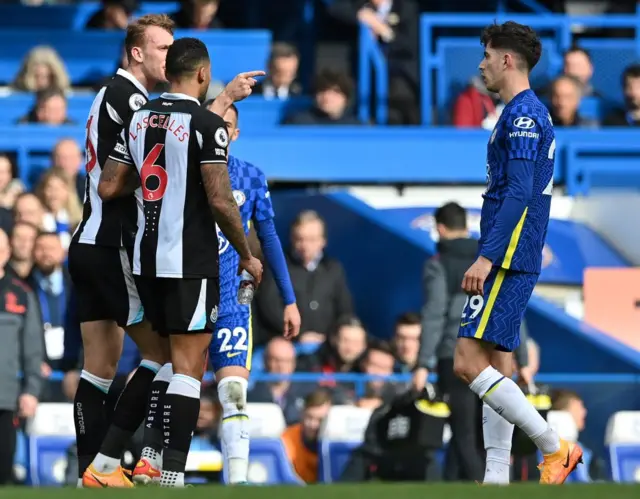 Newcastle's Dan Burn points at Kai Havertz after getting up off the floor following a challenge from the Chelsea forward