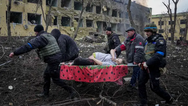 Ukrainian emergency employees and volunteers carry an injured pregnant woman from the damaged by shelling maternity hospital in Mariupol, Ukraine