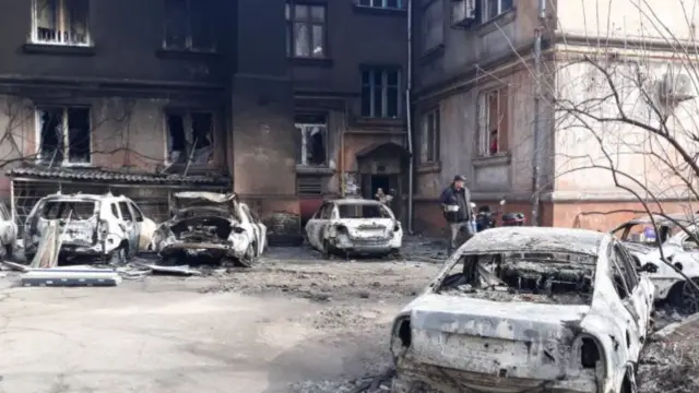 Burnt-out cars, gutted building in Mariupol (undated)