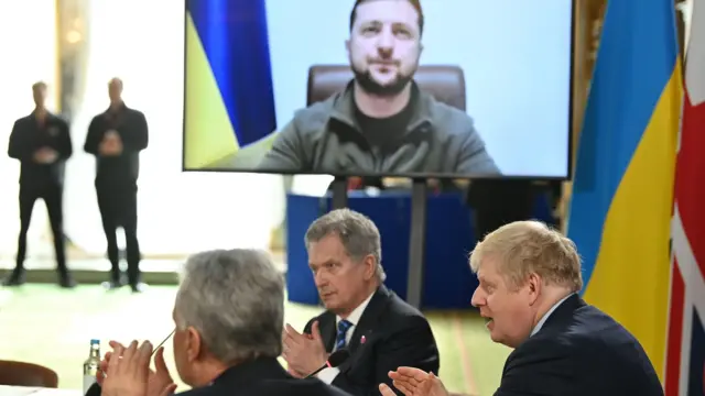 Prime Minister Boris Johnson and attendees applaud after Ukraine"s President Volodymyr Zelensky addressed them by video link during a meeting of the leaders of the the Joint Expeditionary Force (JEF)