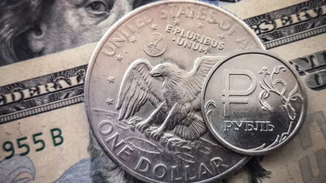 A Russian rouble coin is pictured with US dollar bills and a one dollar coin