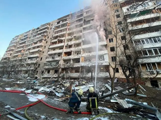 Firefighters directing a water hose to put out the fire at the apartment complex