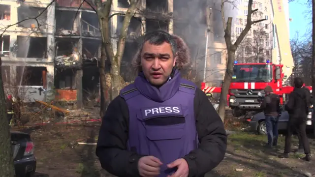 Abdujalil Abdurasulov in front of a damaged building