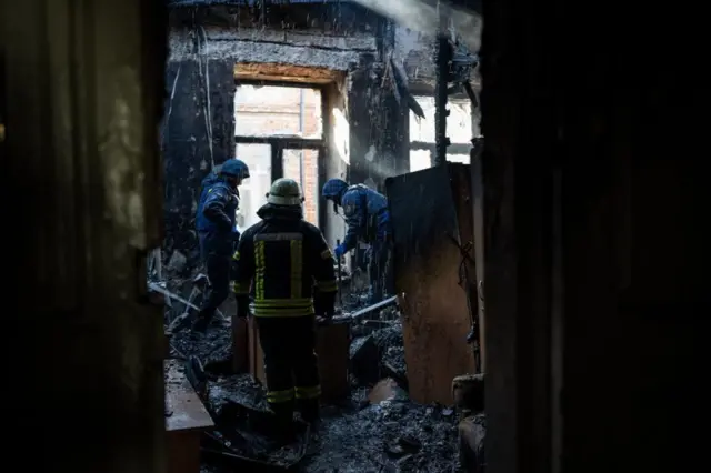 First responders in a building hit by a rocket attack in Kharkiv