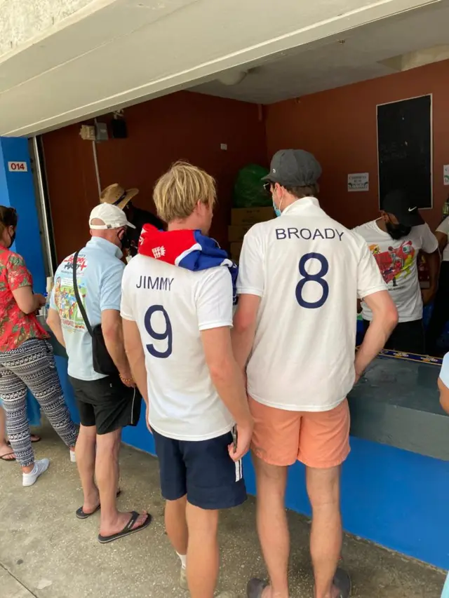 England fans wearing Broad & Anderson shirts queue at a bar