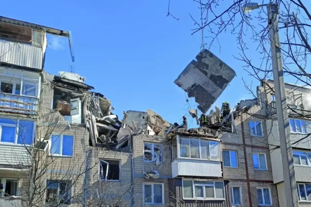 Rescuers remove debris from a residential building damaged by an airstrike, as Russia's attack on Ukraine continues, in Kharkiv, (15 March 2022)