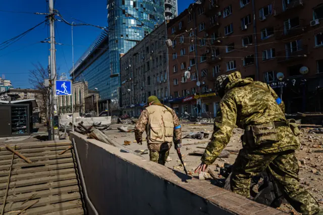 Ukrainian soldiers inspect the damage from a Russian attack in the capital of Kyiv