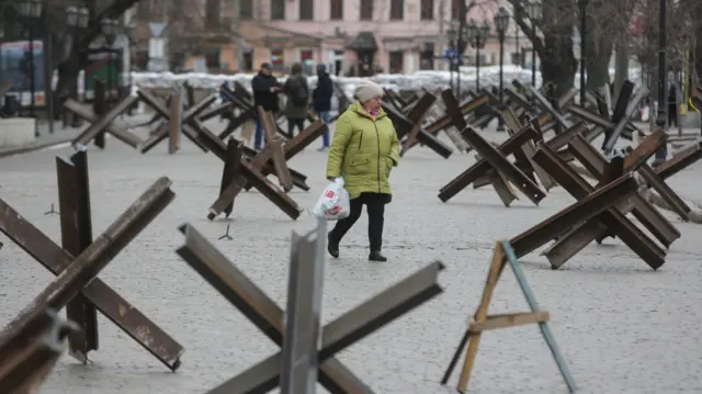 Locals walk on a street between anti-tank Czech hedgehogs in the South Ukrainian city of Odesa,