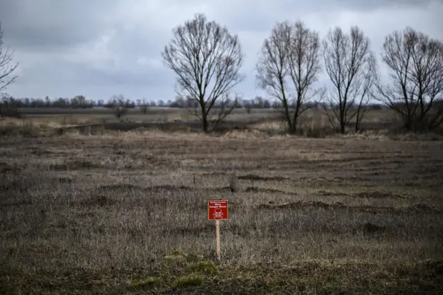 A farmer's field near Kyiv with a warning sign for landmines