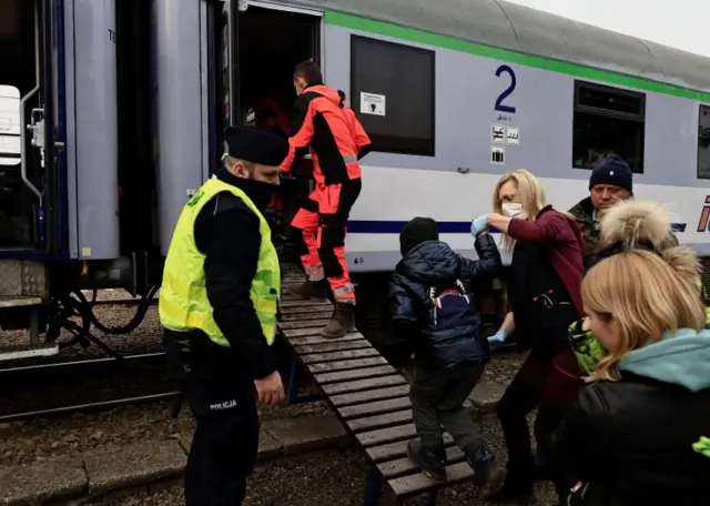 A doctor helps a child, who fled Russia"s invasion of Ukraine, to board a train run by the Polish Red Cross