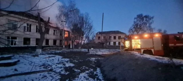 A fire truck parked outside of the burning two-storey building which was hit