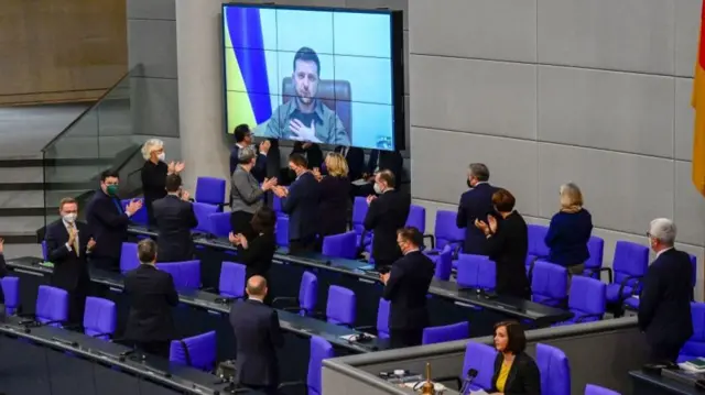 Members of the German government applaud as Ukrainian President Volodymyr Zelensky appears on a screen to address via videolink the German lower house of parliament Bundestag, on March 17, 2022 in Berlin