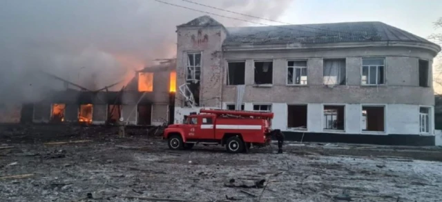 A fire truck parked outside of the burning two-storey building which was hit