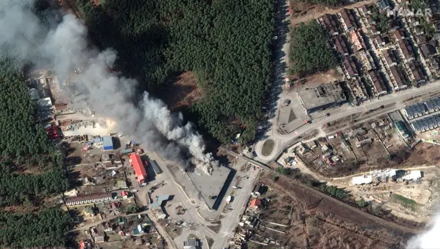 Smoke billows from a grocery store on fire in a damaged residential neighbourhood of Hostomel, in the Kyiv region