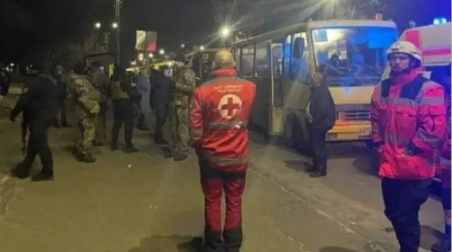 Rescuers and officers in fatigues help usher fleeing civilians onto waiting buses leaving the Kyiv region