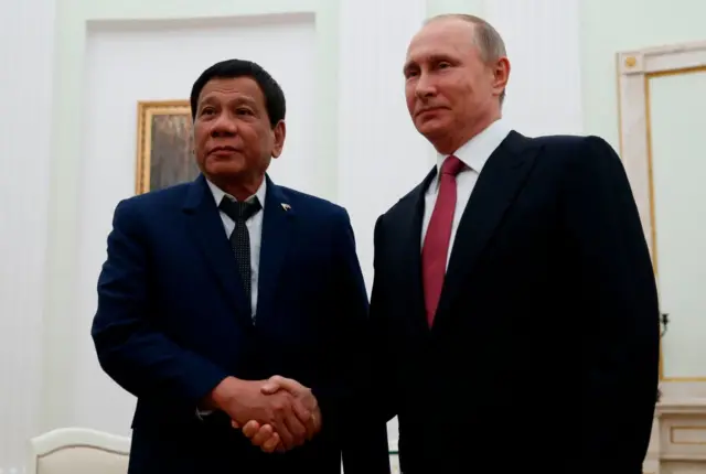 Russian President Vladimir Putin (R) shakes hands with his Philippine counterpart Rodrigo Duterte