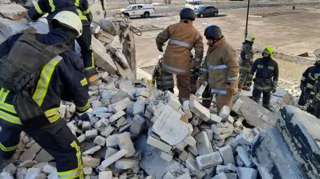 Emergency services work through rubble