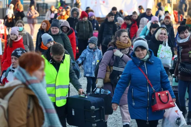 Refugees cross the border from Ukraine to Poland at a border checkpoint in Kroscienko