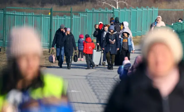 Refugees fleeing the Russian invasion cross the border from Ukraine to Poland