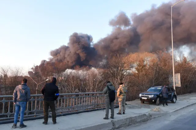 People watch the smoke rise over Lviv