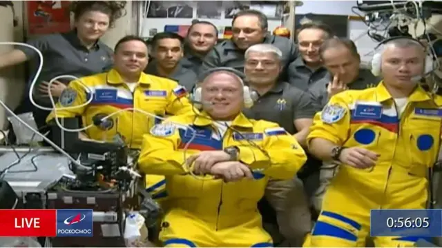 A group of Russian cosmonauts wearing bright yellow uniforms with blue trims.