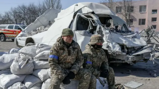 Soldiers sit next to military barracks