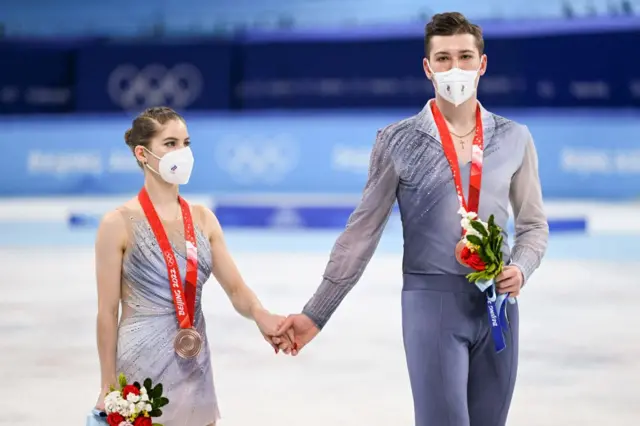 Bronze medallists Russia's Anastasia Mishina and Russia's Aleksandr Galliamov attend the venue ceremony of the pair skating figure skating event during the Beijing 2022 Winter Olympic Games at the Capital Indoor Stadium in Beijing on February 19, 2022.