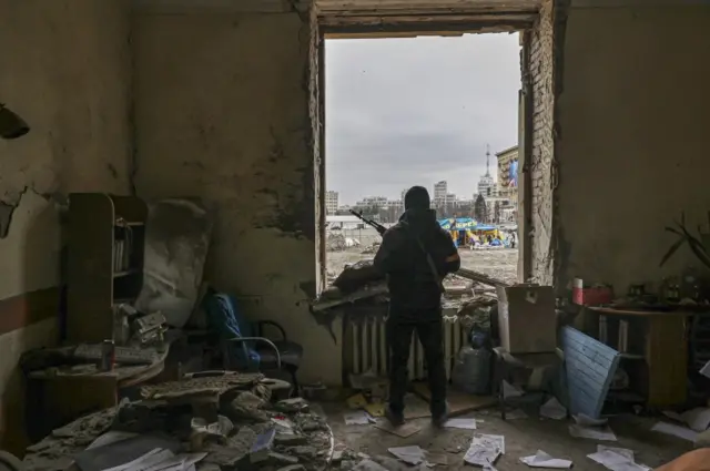 A member of the Territorial Defense Forces of Ukraine stands inside the damaged government building in the aftermath of a shelling in Kharkiv