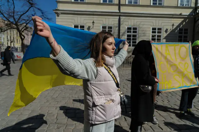 A woman in Lviv holds a Ukrainian flag during a rally in support of Mariupol while calling for a no-fly zone