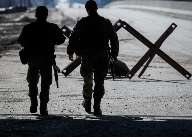 Ukrainian service members walk at a position on the front line in the Kyiv region