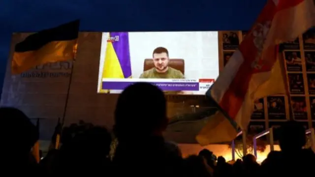 People watch President Zelensky's address outside the Israeli parliament