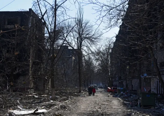 Residents walk among rubble in Mariupol