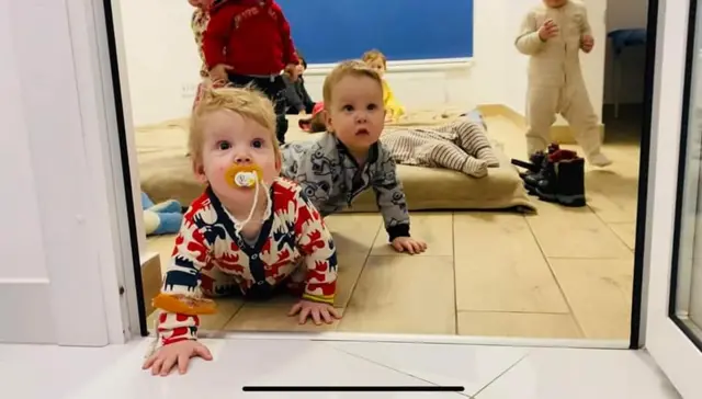 Two babies crawl towards a doorway