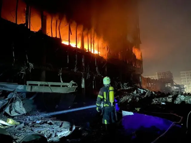 Firefighters tackle a blaze at a shopping centre after a Russian shelling in the Podilskyi district of Kyiv