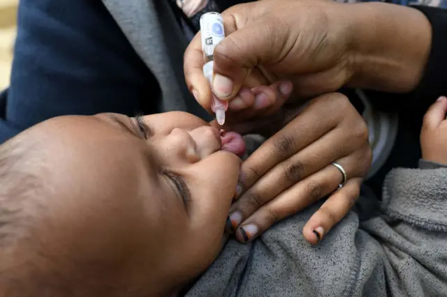 A health worker delivers a polio vaccine