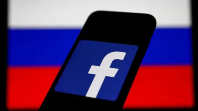 Facebook logo displayed on a phone screen and Russian flag