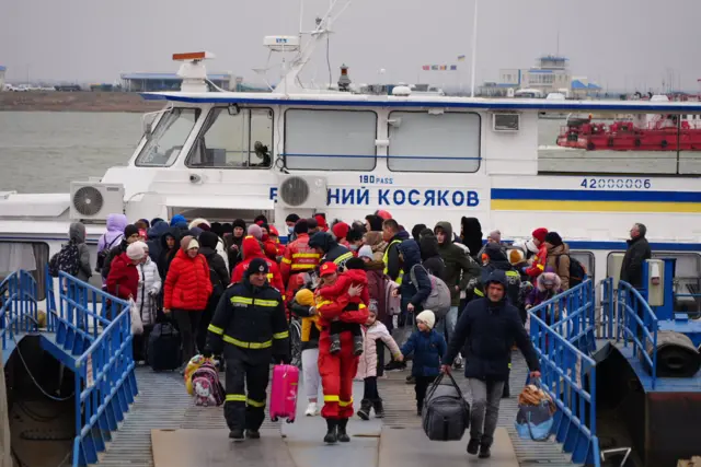 Women and children are helped off the boat from Ukraine by the Romanian Fire Brigade