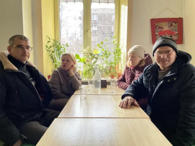 Oksana sits in a cafe with her husband and parents