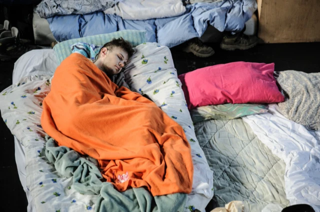 A young man sleeps at a converted gym for refugees in Lviv